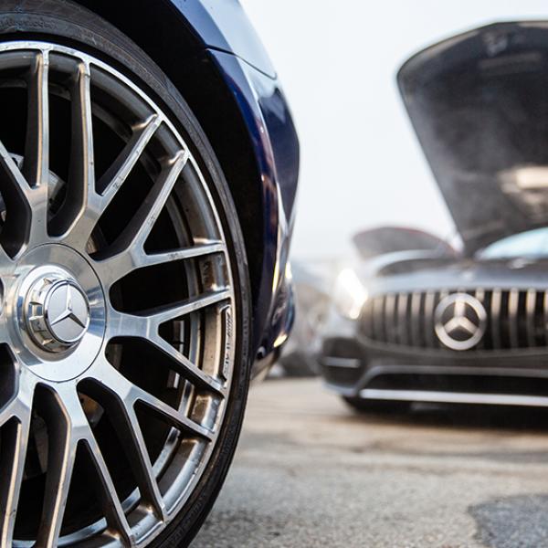 Rim and tire close up with another Mercedes worked on in the background