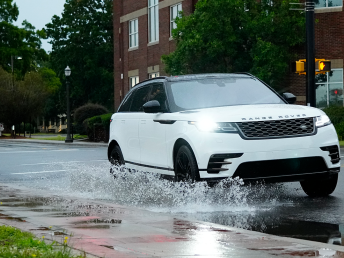 White Car driving through puddle on street